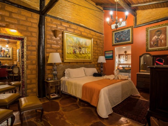 Quarto da pousada de luxo com cama de casal e ambiente rústico decorado