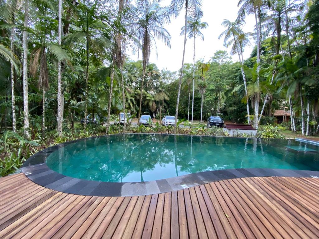 Visão da piscina no glamping, com deck de madeira e natureza ao redor.