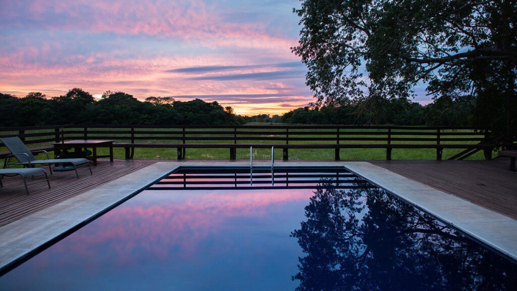 Vista de um por do sol a partir do deck de uma piscina na pousada.