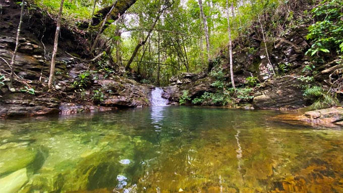 Imagem de um dos poços de água da cachoeira das loquinhas, envolto em árvores e vegetação.