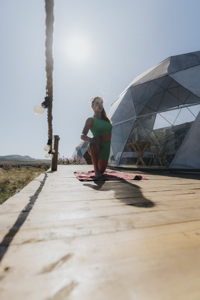 Rachel Appolonio fazendo yoga na frente do domo do Glamping Hidden Treasure na Chapada dos Veadeiros